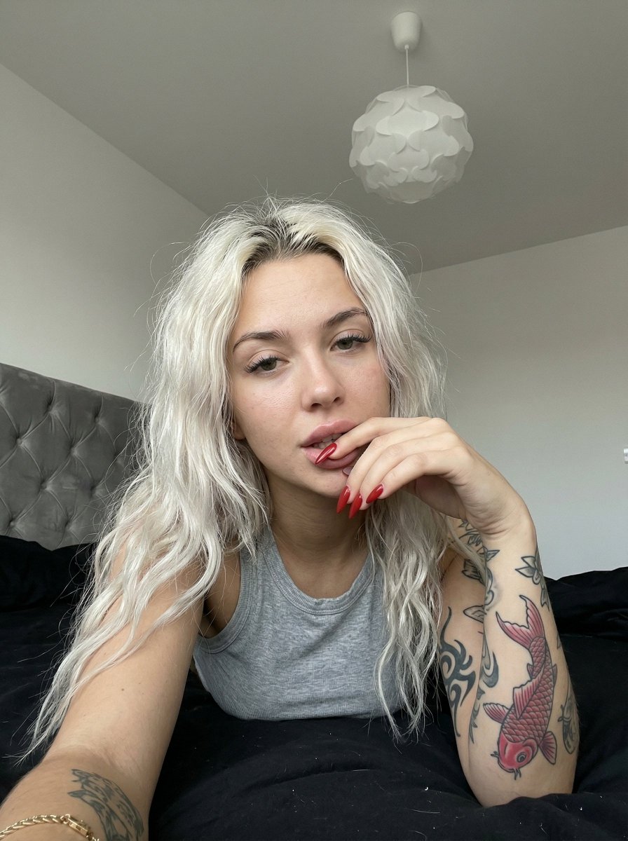 Casual smartphone photo of a tattooed woman in a bedroom — example 1