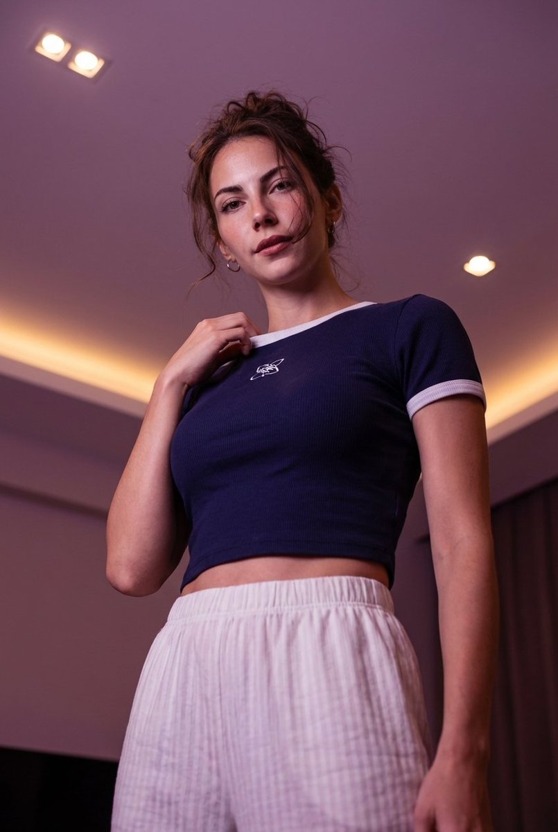 Low-angle stylized portrait of a young woman in a dim room — example 1
